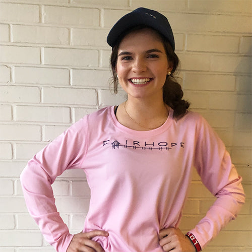 Young, brunette, caucasian girl wearing a black ball cap and and pink long-sleeved t-shirt with the word 